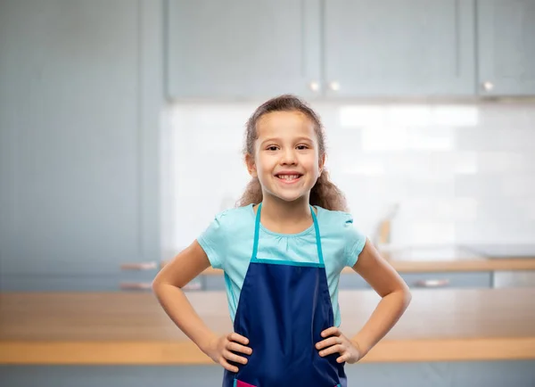 Усміхнена дівчинка в фартусі над домашньою кухнею — стокове фото