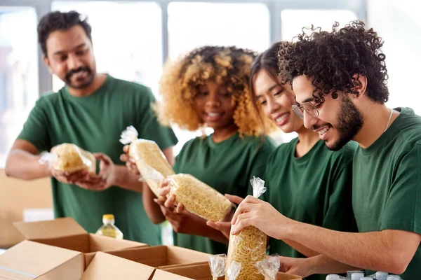 Szczęśliwi wolontariusze pakujący żywność w pudełka darowizn — Zdjęcie stockowe