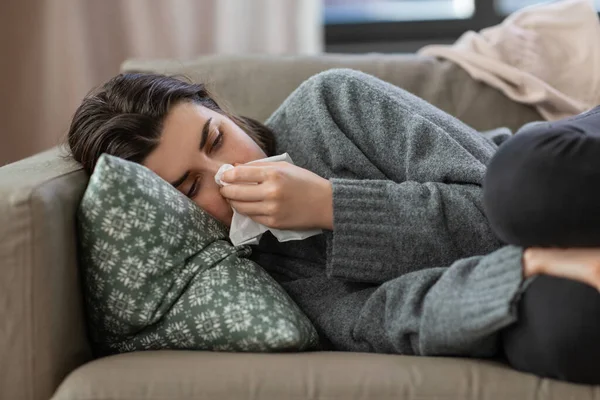 Triste femme pleurant avec des tissus couchés sur le canapé à la maison — Photo