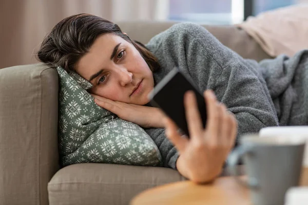 Stressed woman with smartphone on sofa at home — Foto de Stock