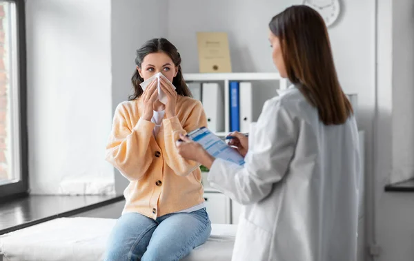 Female doctor and woman blowing nose at hospital —  Fotos de Stock