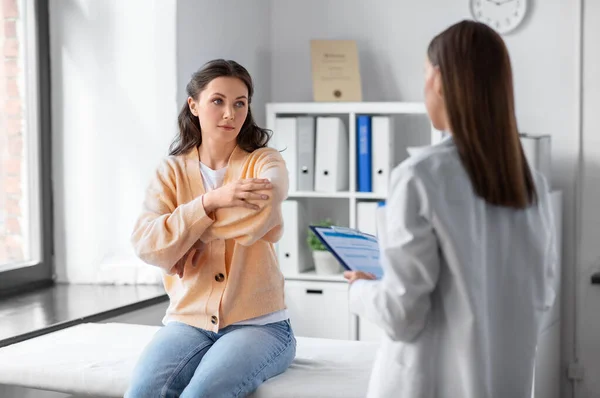 Female doctor and woman with sore arm at hospital — Fotografie, imagine de stoc