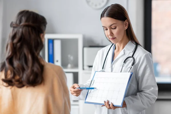 Doctor showing cardiogram to woman at hospital — Foto Stock
