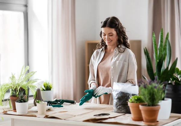 Mulher feliz com luvas plantando flores em casa — Fotografia de Stock