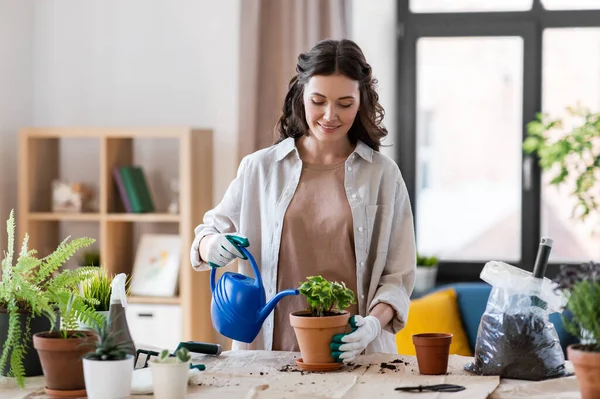 Happy woman planting pot flowers at home — Stock Photo, Image