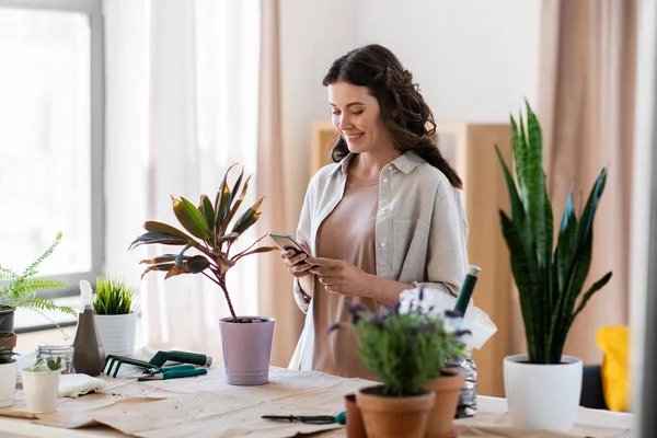 Frau mit Smartphone und Topfblume zu Hause — Stockfoto