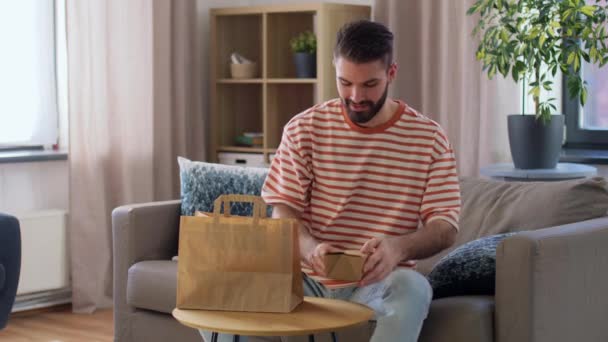 Усміхнений чоловік розпаковує їжу вдома — стокове відео
