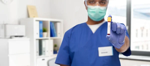 Médico masculino mascarado com sangue no tubo de ensaio — Fotografia de Stock