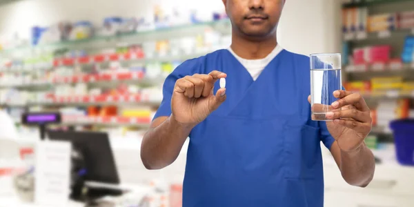 Médico masculino con medicina y agua en la farmacia — Foto de Stock