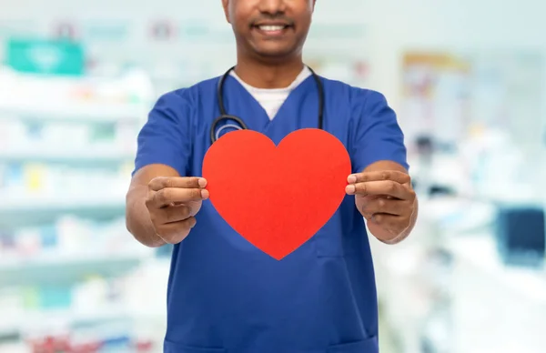 Lekarz lub pielęgniarka z czerwonym sercem w aptece — Zdjęcie stockowe