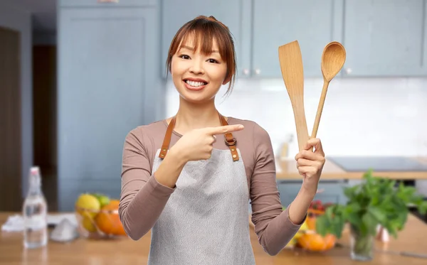 Femme dans tablier avec cuillère et spatule dans la cuisine — Photo