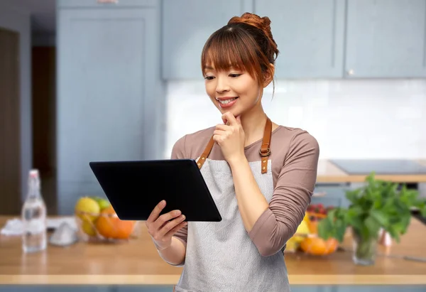 Mujer feliz en delantal con tableta pc en la cocina — Foto de Stock