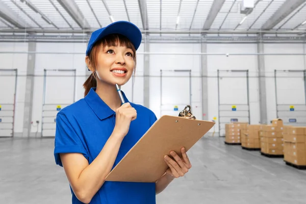 Delivery woman with clipboard and pen at warehouse — Stock Photo, Image