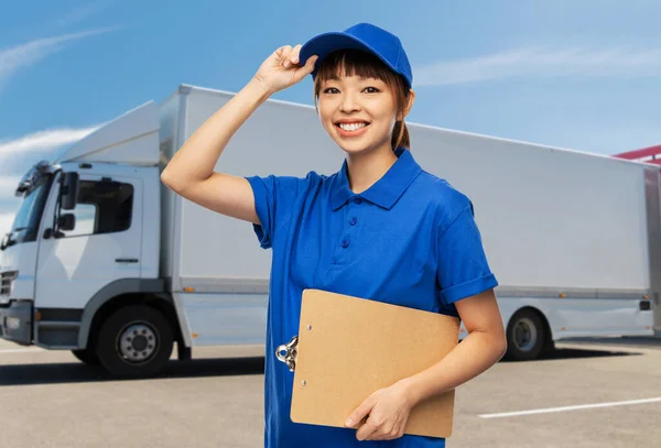 Happy delivery woman with clipboard over truck — Stock Photo, Image