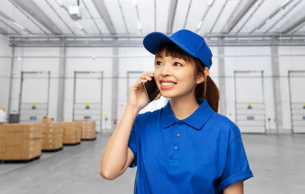 Gelukkige levering vrouw bellen op de telefoon in het magazijn — Stockfoto