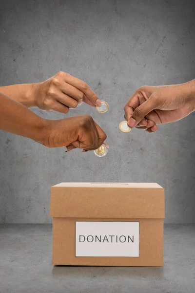Закрыть руки, кладущие монеты в ящик для пожертвований — стоковое фото