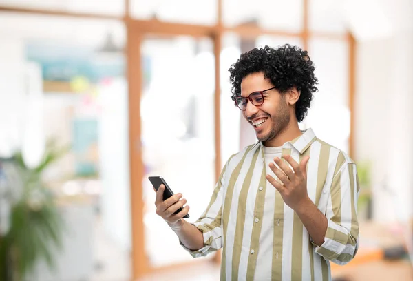 Feliz joven sonriente con teléfono inteligente en la oficina — Foto de Stock