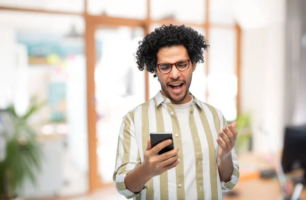 Joven disgustado con teléfono inteligente en la oficina — Foto de Stock