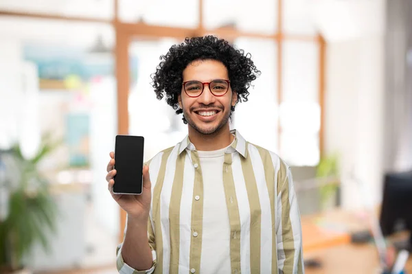 Šťastný muž v brýlích ukazující smartphone v kanceláři — Stock fotografie