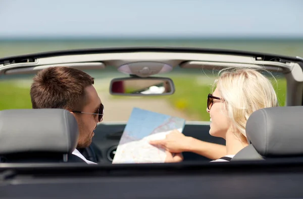 couple with road map driving in convertible car