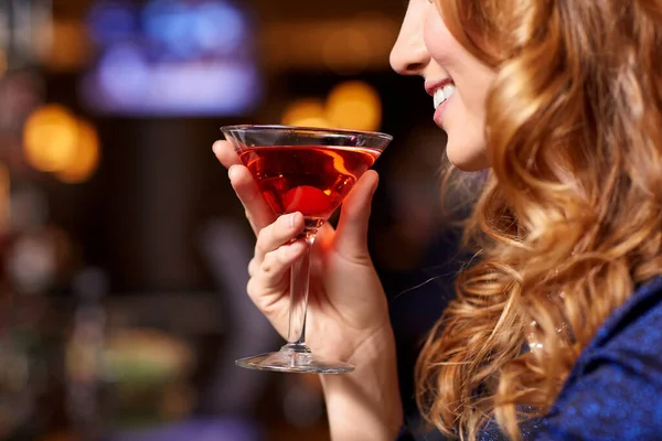 Mujer sonriente bebiendo cóctel en el club nocturno — Foto de Stock