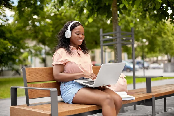 Studente africano ragazza in cuffia con computer portatile — Foto Stock