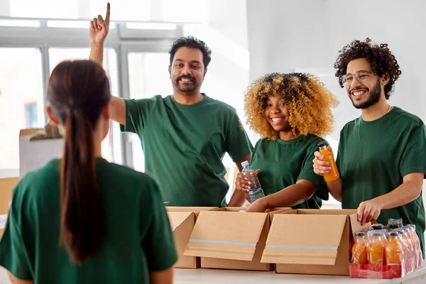 Voluntarios felices empacando comida en cajas de donaciones —  Fotos de Stock