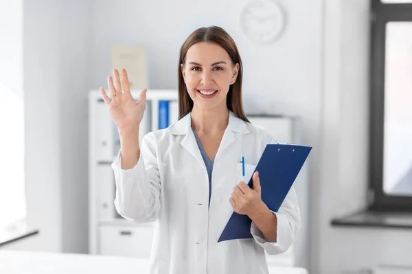 Lachende vrouwelijke arts met klembord in het ziekenhuis — Stockfoto
