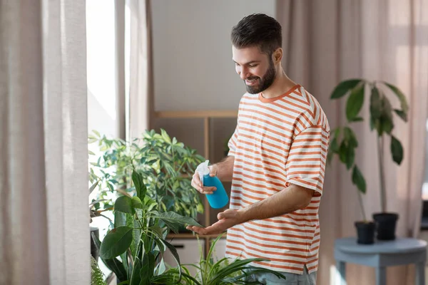 Чоловік обприскує кімнатну рослину водою вдома — стокове фото