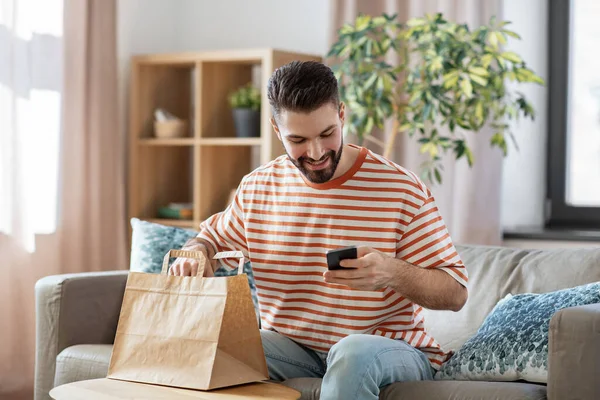 Homme avec téléphone vérifier la commande de nourriture à la maison — Photo