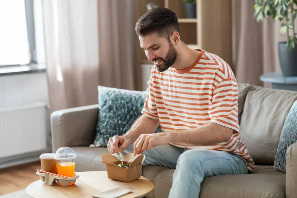 Lächelnder Mann isst zu Hause Essen zum Mitnehmen — Stockfoto