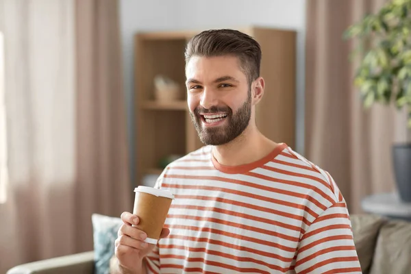 Uomo sorridente bere caffè da asporto a casa — Foto Stock