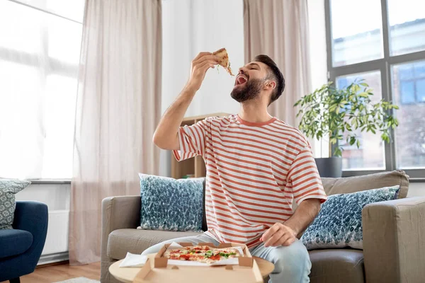 Hombre feliz comiendo pizza para llevar en casa — Foto de Stock
