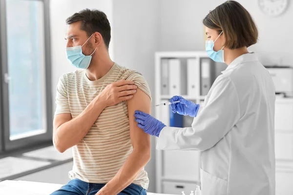 Médico com seringa vacinando paciente masculino — Fotografia de Stock