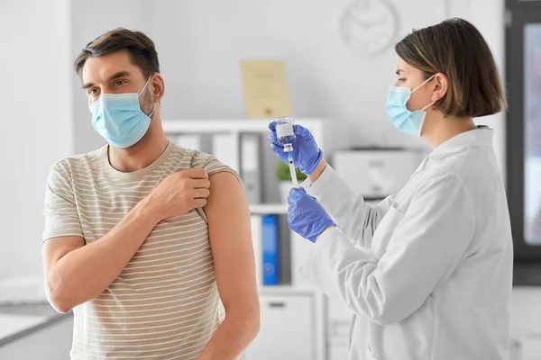 Lékař s injekční stříkačkou vakcinující mužského pacienta — Stock fotografie