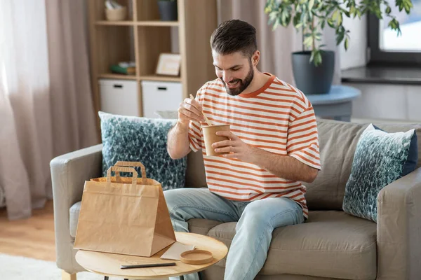 Smiling man eating takeaway food at home Fotos De Stock Sin Royalties Gratis