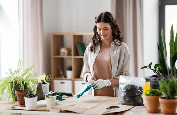 Happy woman with gloves planting flowers at home —  Fotos de Stock