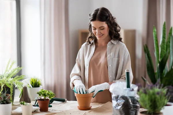 Mujer feliz plantando flores de maceta en casa —  Fotos de Stock