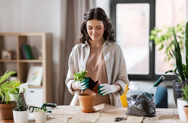 Happy woman planting pot flowers at home — Zdjęcie stockowe