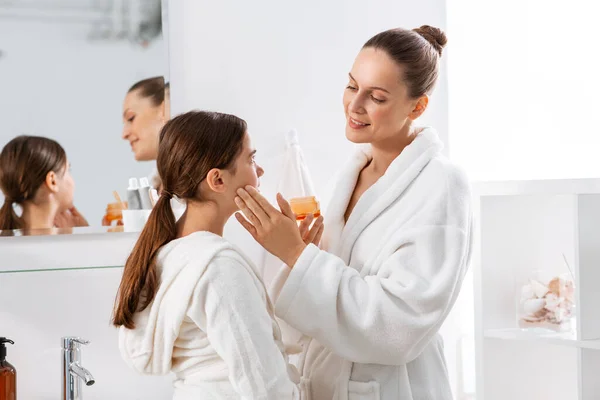Moeder en dochter met moisturizer op badkamer — Stockfoto