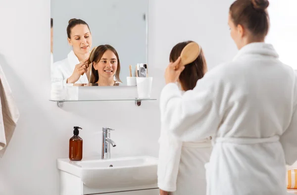 Moeder en dochter borstelen haar op badkamer — Stockfoto