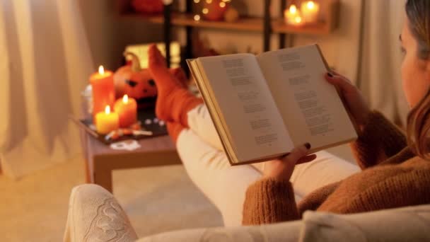 Młoda kobieta czyta książkę w domu na Halloween — Wideo stockowe
