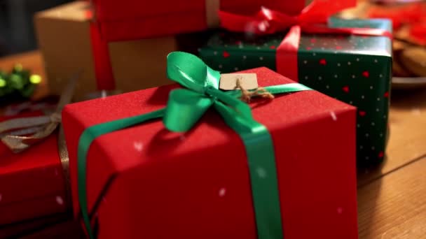 Упаковані різдвяні подарунки на дерев'яному столі над снігом — стокове відео