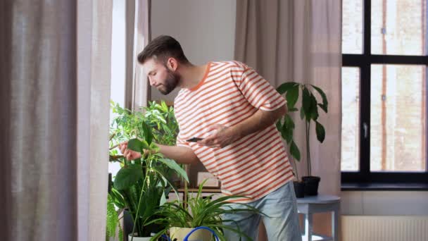 Hombre con smartphone y flores en casa — Vídeos de Stock