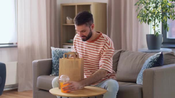 Smiling man eating takeaway food at home — Stock videók