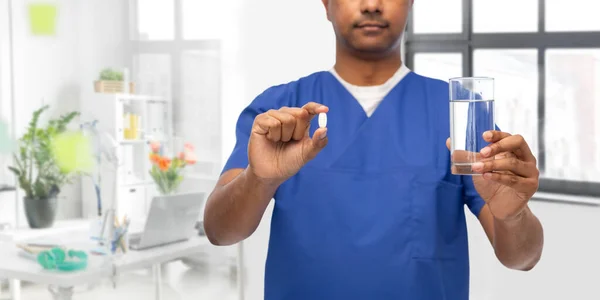 Лікар або медсестра чоловічої статі з лікарською таблеткою та водою — стокове фото