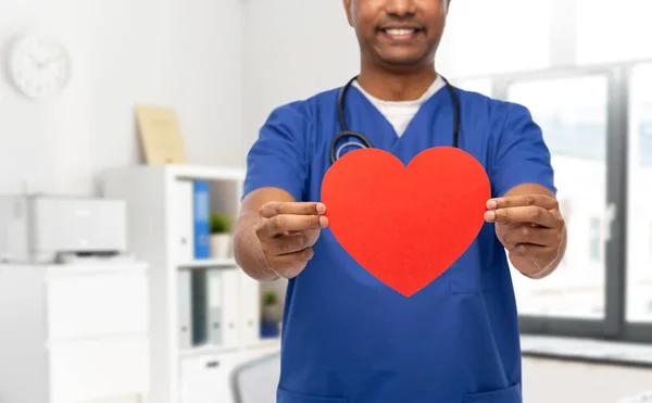 Uśmiechnięty lekarz lub pielęgniarka z czerwonym sercem — Zdjęcie stockowe