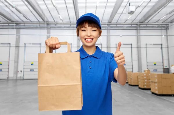 Delivery woman with paper bag showing thumbs up — Stock Photo, Image