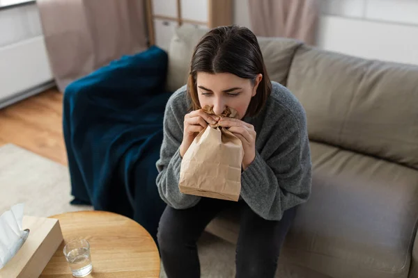 Женщина с приступом паники дышит в мешок дома — стоковое фото