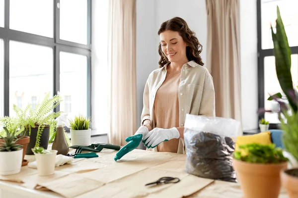 Happy woman with gloves planting flowers at home — Stock Photo, Image